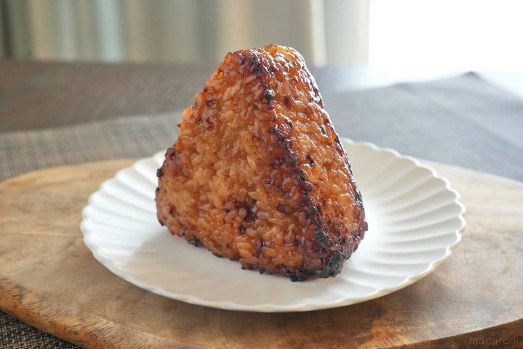 木のカッティングボードと白い皿にのった冷凍の焼きおにぎり