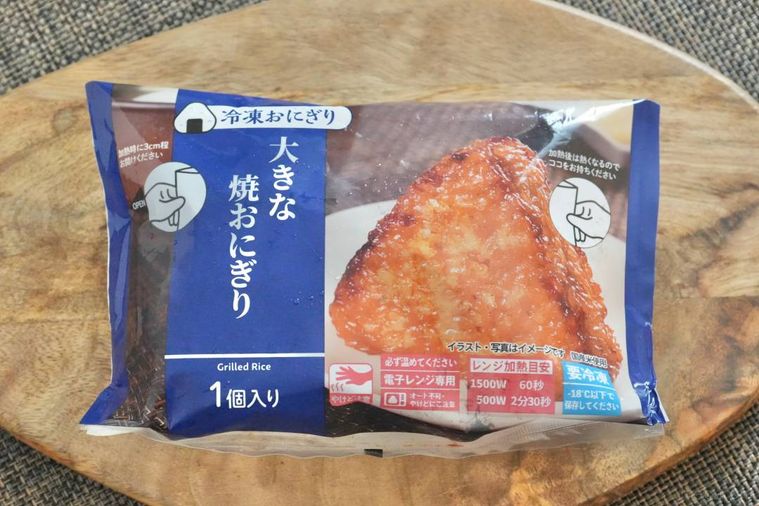 木のカッティングボードにのった青色のパッケージの冷凍焼きおにぎり