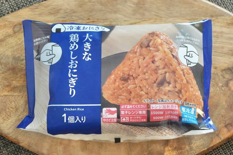 木のカッティングボードにのった青色のパッケージの冷凍鶏めしおにぎり
