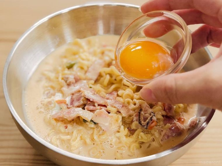 カルボナーラ風にアレンジした辛ラーメンに卵黄をのせようとしている様子