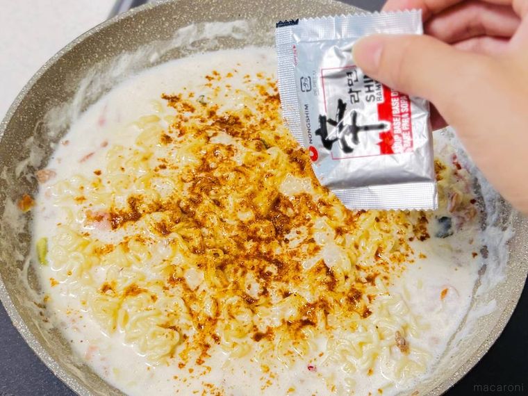 牛乳と水で煮た辛ラーメンに粉末スープを加えている様子