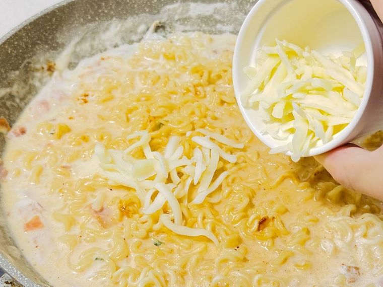 牛乳と水で煮た辛ラーメンにチーズを加えている様子
