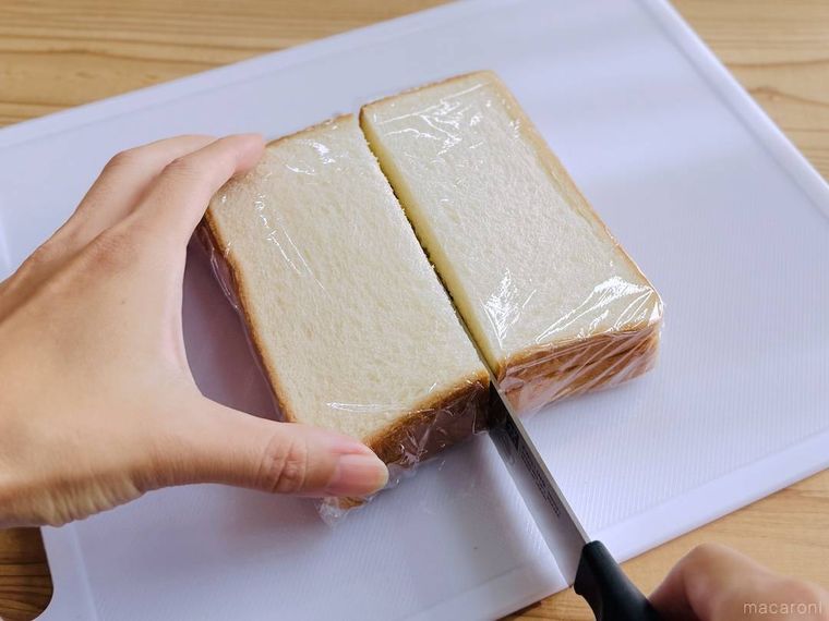 ラップで包んだたまごサンドを包丁でカットしている様子