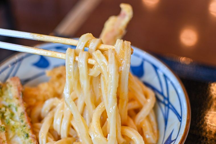 丸亀製麺の釜玉うどんを持ち上げているところ