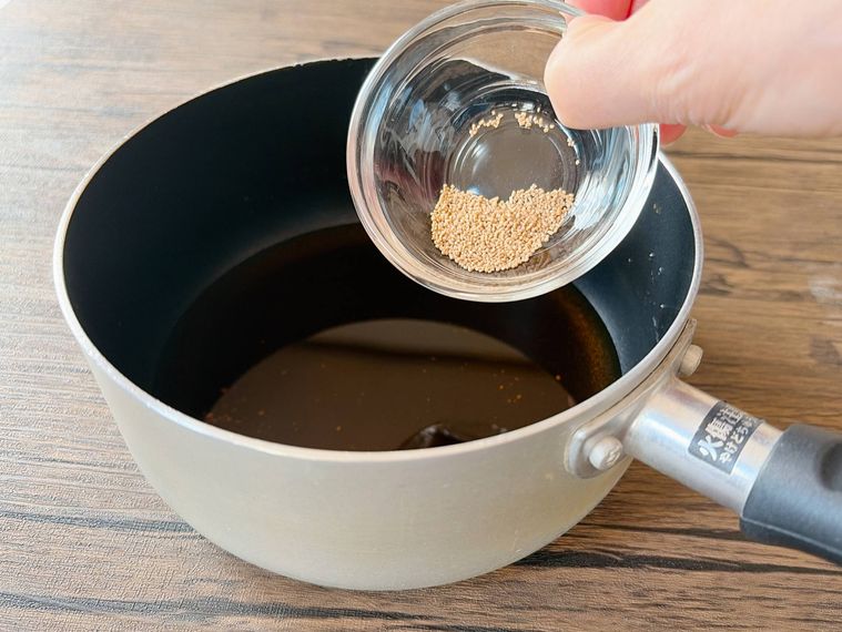 調味料が入った鍋に和風だしの素を加える様子