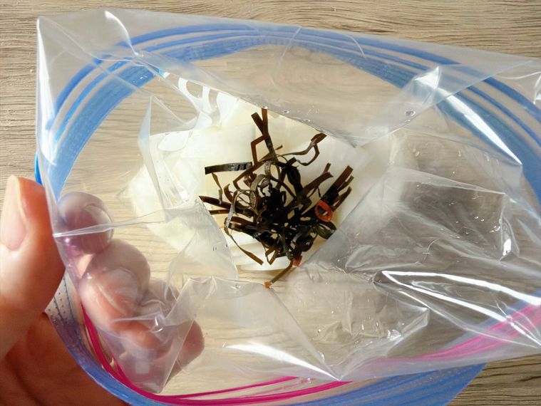 大根の甘酢漬けが入ったジッパー付き保存袋に昆布や輪切り唐辛子を入れた様子