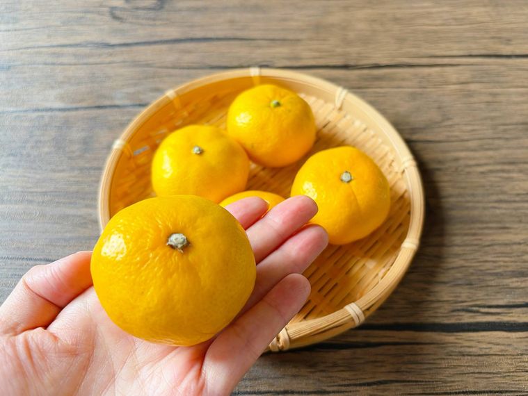 ザルに盛られたみかん、手に持ったみかん
