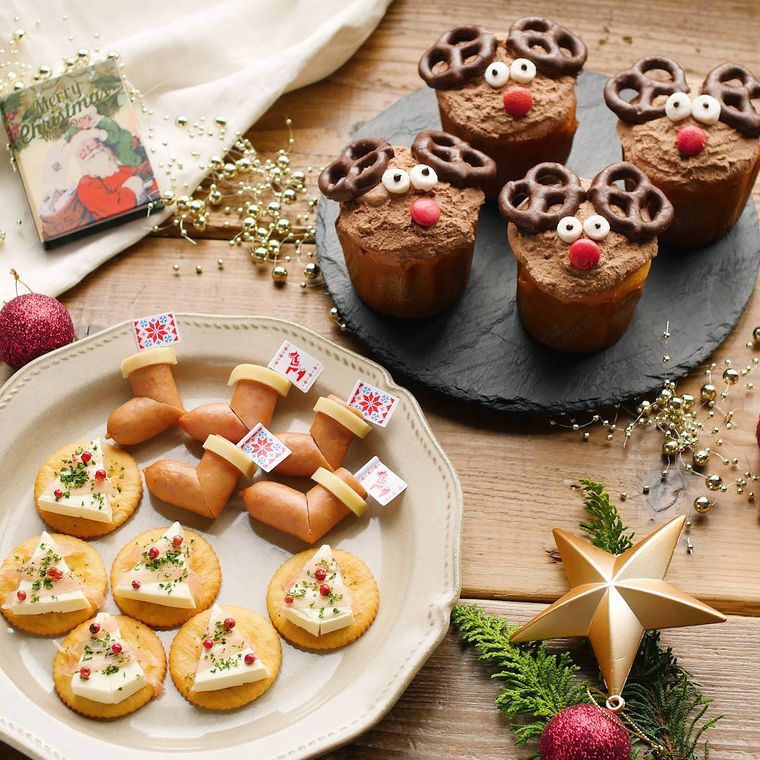 白い皿に盛り付けられたクリスマス風の前菜と、黒い皿に盛り付けられたトナカイのカップケーキ