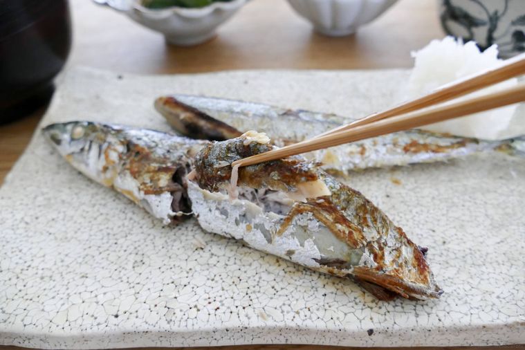 フライパンで焼いたさんまを箸でもぐして持ち上げる様子