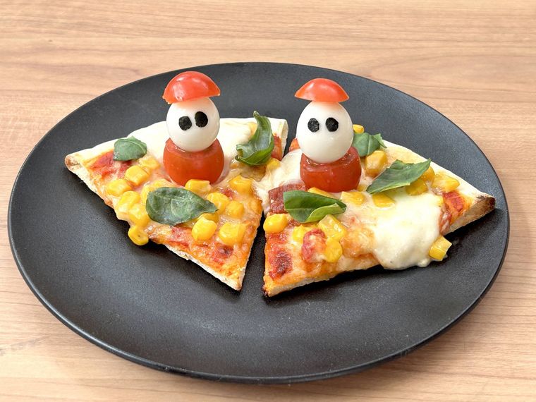 ミニトマトサンタのクリスマスピザが黒い皿に盛り付けられているところ