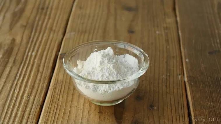 木のテーブルに置かれた、ガラスのボウルに入った強力粉