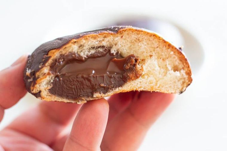 半分にカットしたファミリーマート本気のチョコクリームパンを手で持っている