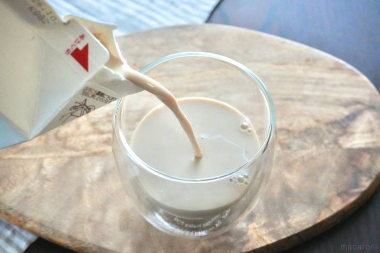 ロイヤルミルクコーヒーのパックから木のカッティングボードにのったグラスへ中身を注ぐ様子