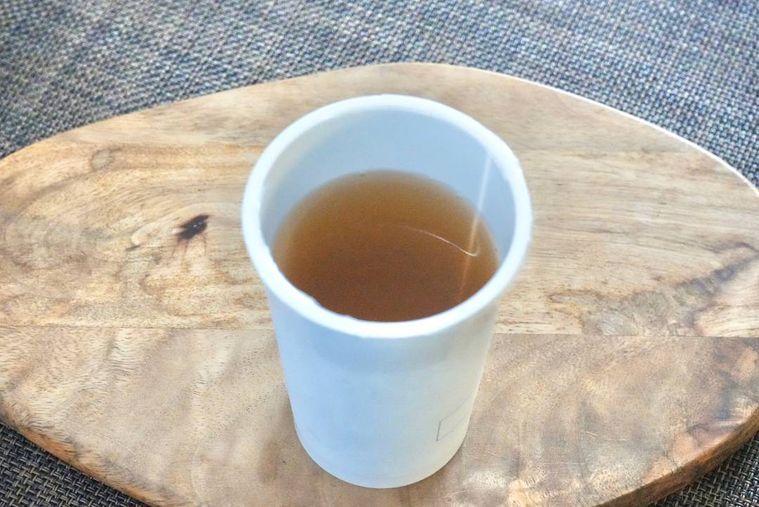 木のカッティングボードにのった飲むおだしのカップ飲料