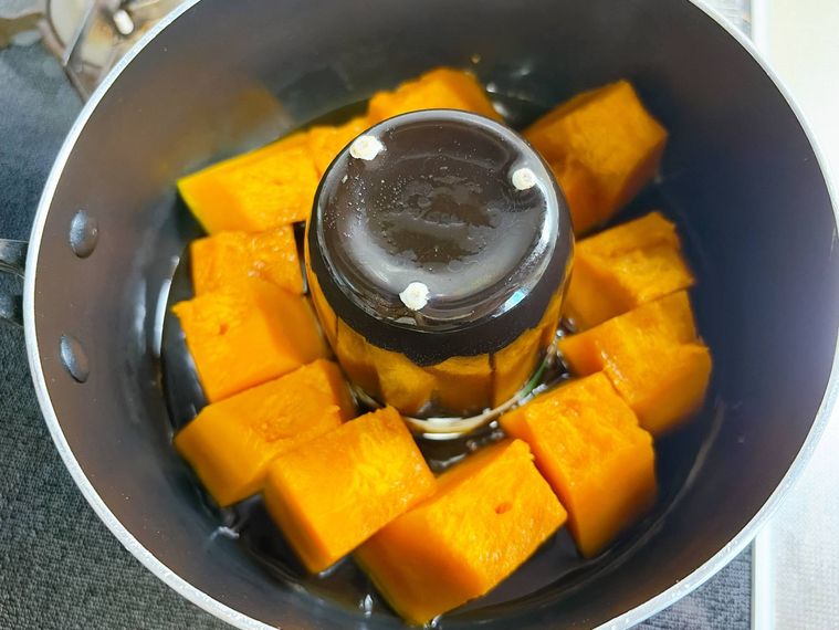 鍋に湯呑みを入れてかぼちゃの煮物を作る様子