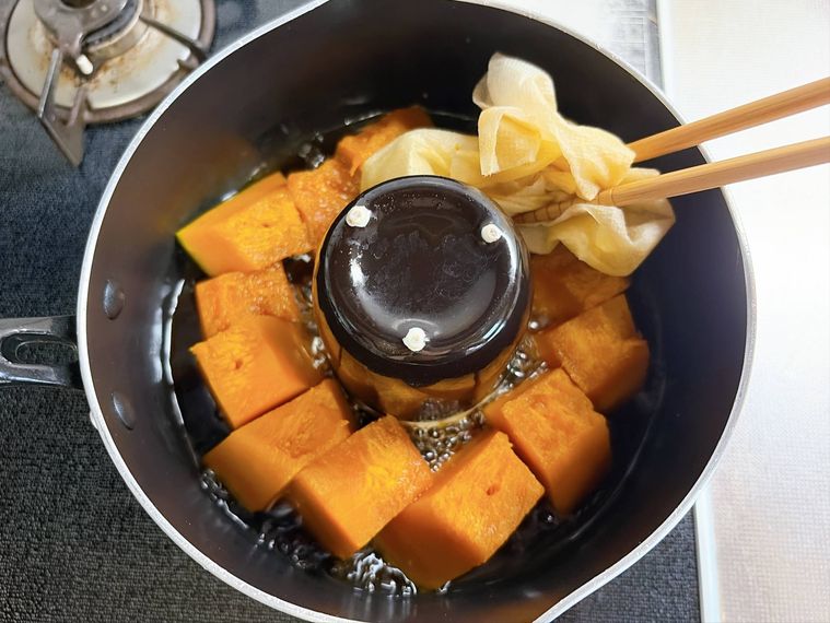 かぼちゃの煮物の落とし蓋を外す様子