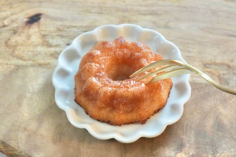 木のカッティングボードと白い小皿にのったコンビニのバター餅を金色のフォークで食べる様子