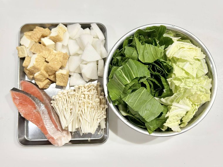 鮭や大根、厚揚げ、白菜などの鍋具材が並んでいる様子