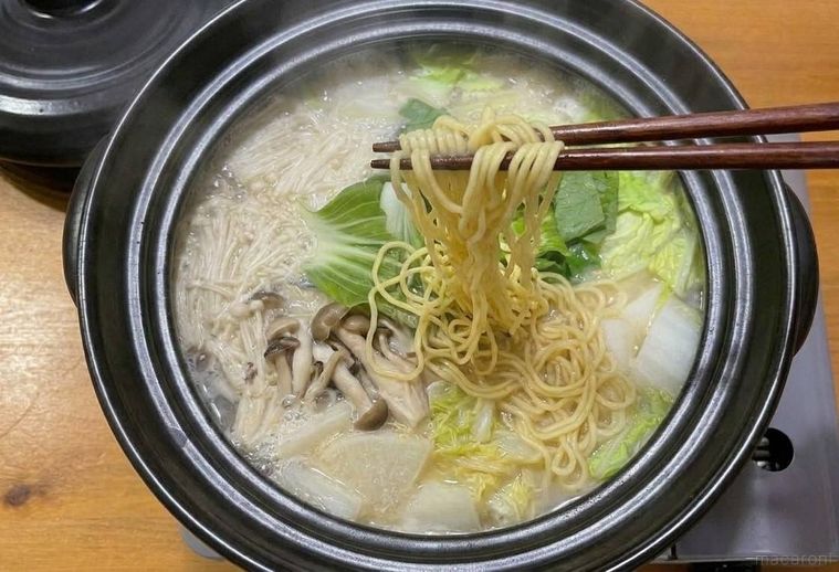 鍋のラーメンを箸ですくっている様子