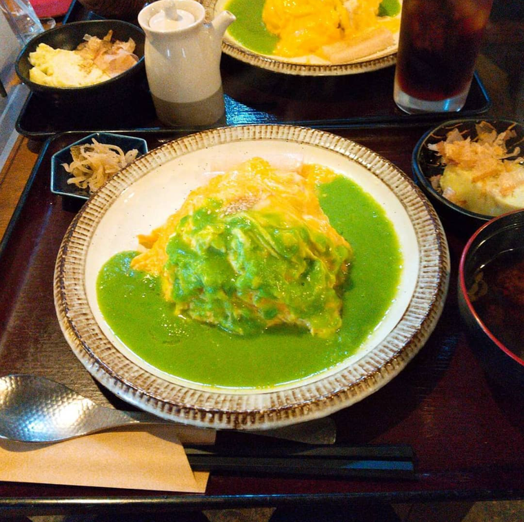 白い大皿に盛られたグリーンピースソースがかかったじゃこ山椒のオムライス