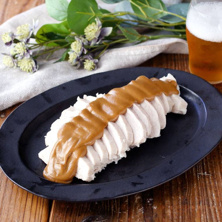 黒い皿に盛られたタレがかかった蒸し鶏