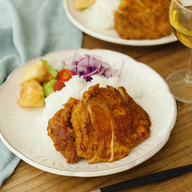 白い皿に盛りつけられたタンドリーポークにごはんと野菜が添えられている