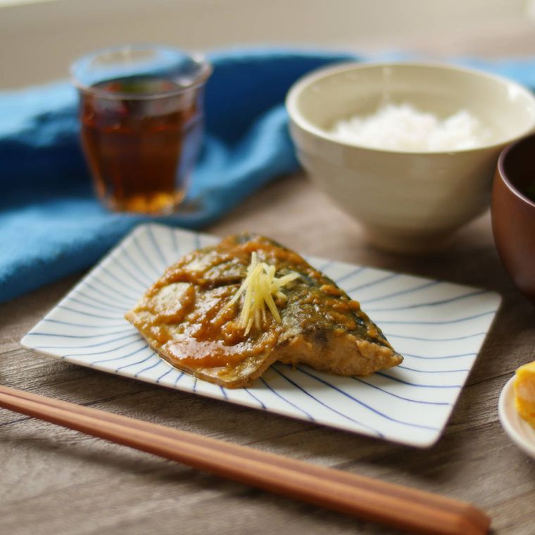 和食器に盛りつけられたさばのみそ煮にごはん、みそ汁、お茶が添えられている