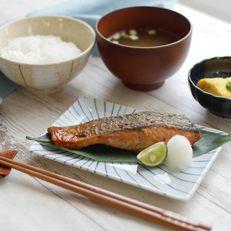 鮭の西京焼き、ごはん、みそ汁、小鉢が添えられた食卓