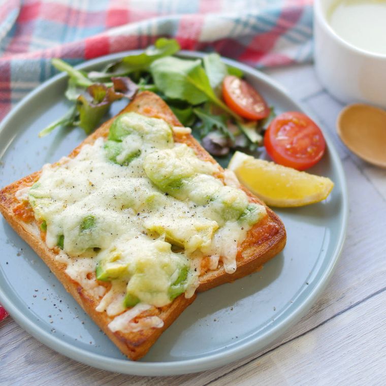 丸い皿に野菜と一緒に盛られた、アボカドのせ鮭マヨトースト