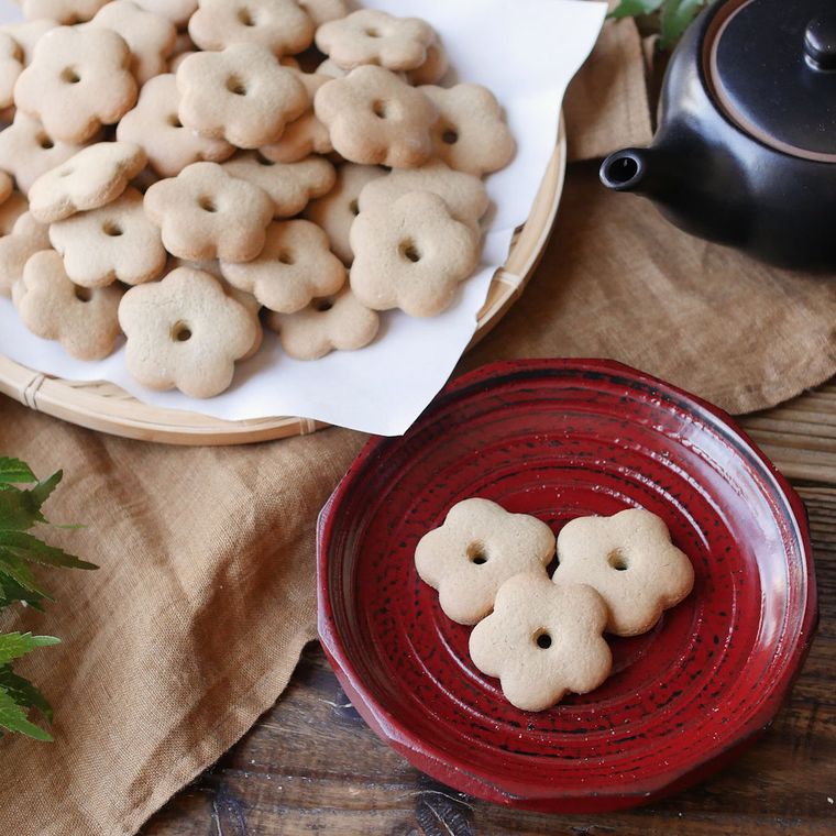 紙を敷いた大きな皿と赤い小皿に盛られた、そばぼうろ