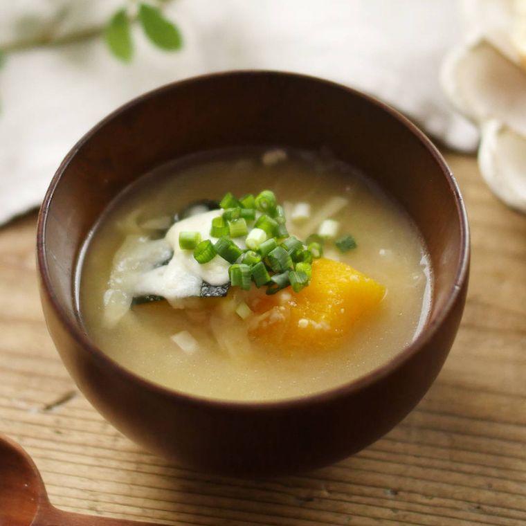 お椀に小葱が散らされたかぼちゃとチーズのみそ汁が入っている