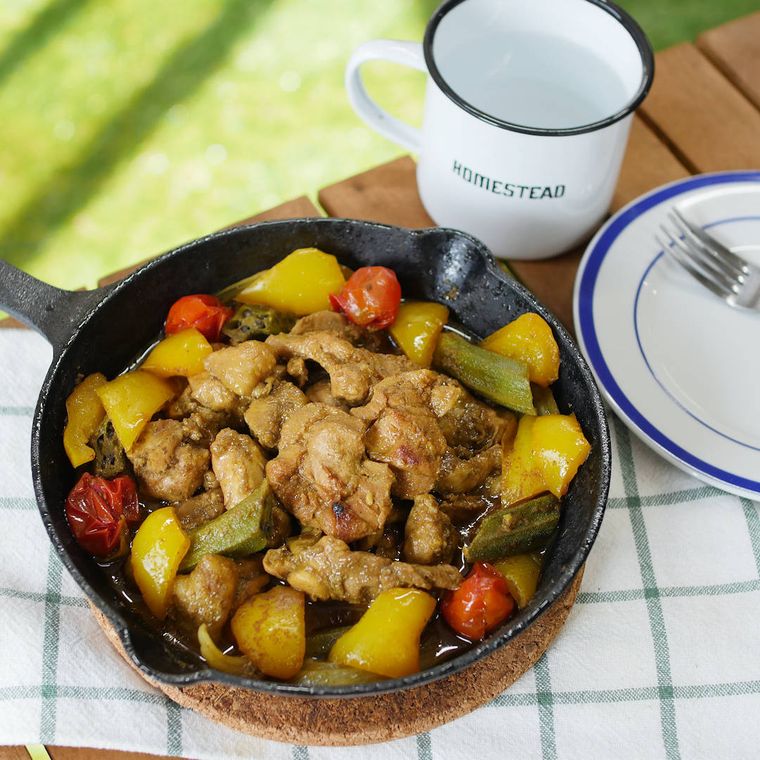 コルクにのせたスキレットのタンドリーチキンと白いマグカップ