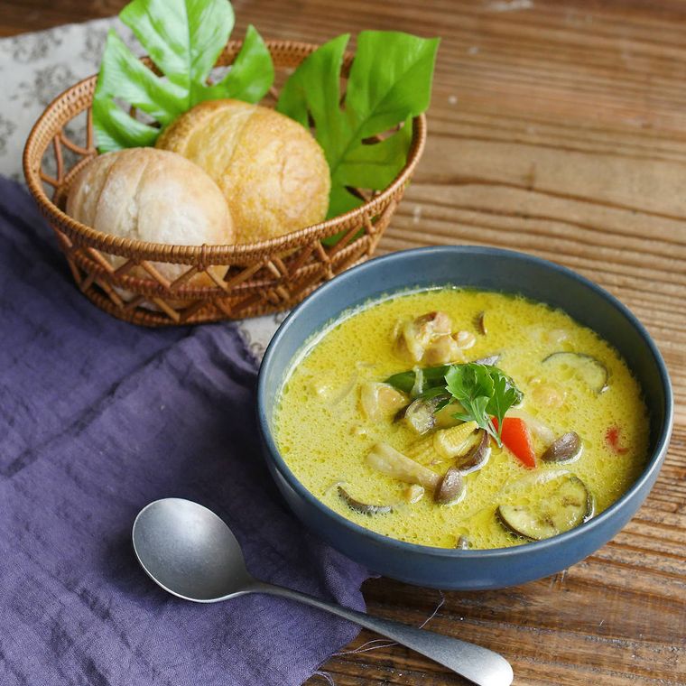 青いボウルに盛りつけられた鶏肉と野菜たっぷりなカレースープ