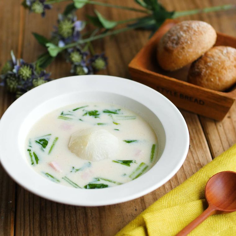 白い皿に盛りつけられたかぶの実と葉入りのバタみそ豆乳スープ