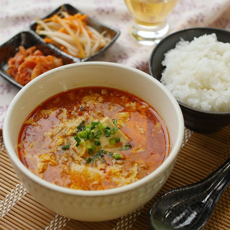 白いお椀に入っている豆腐入り麻婆スープとご飯、お漬物など