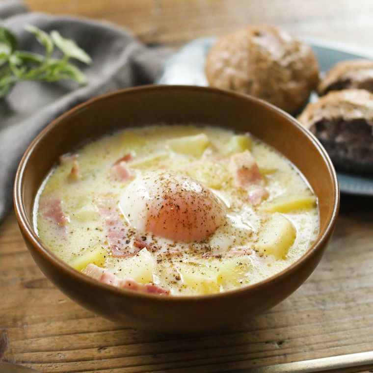 ブラウン色のボウルに盛りつけられた温泉卵のせ豆乳じゃがスープ