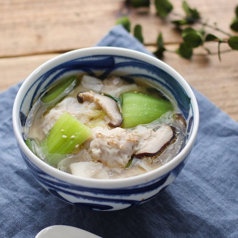 お椀に入っている肉入りワンタンとチンゲン菜の中華スープ