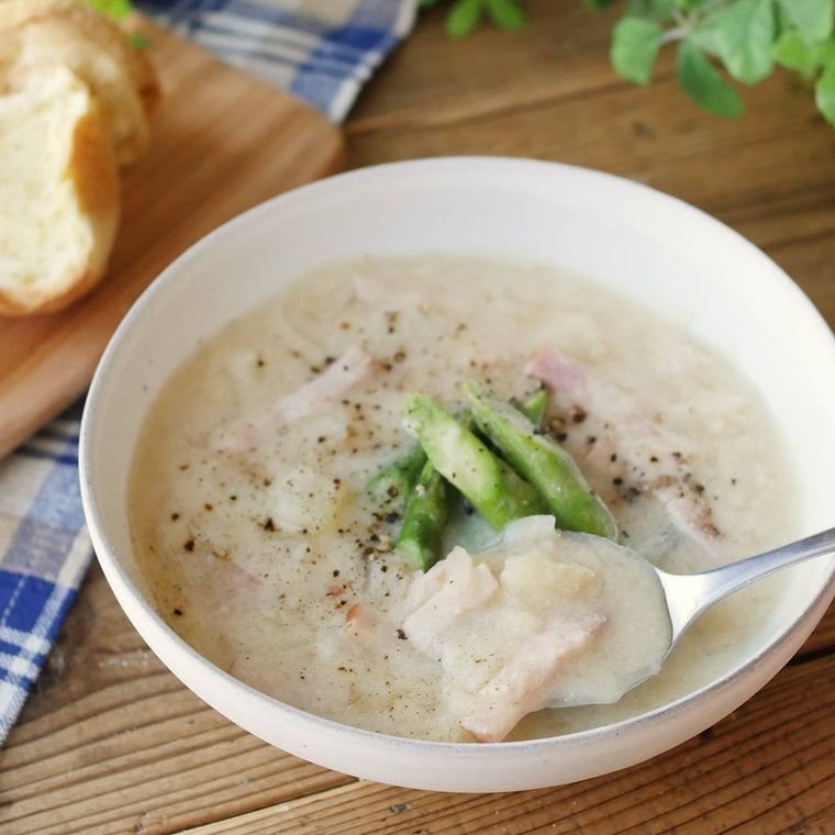 白いボウルに盛りつけられたじゃがいもとアスパラの豆乳みそスープ