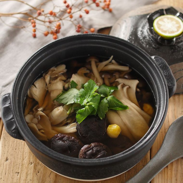 黒い土鍋に入っているしめじやまいたけ、エリンギなどの蒸し煮
