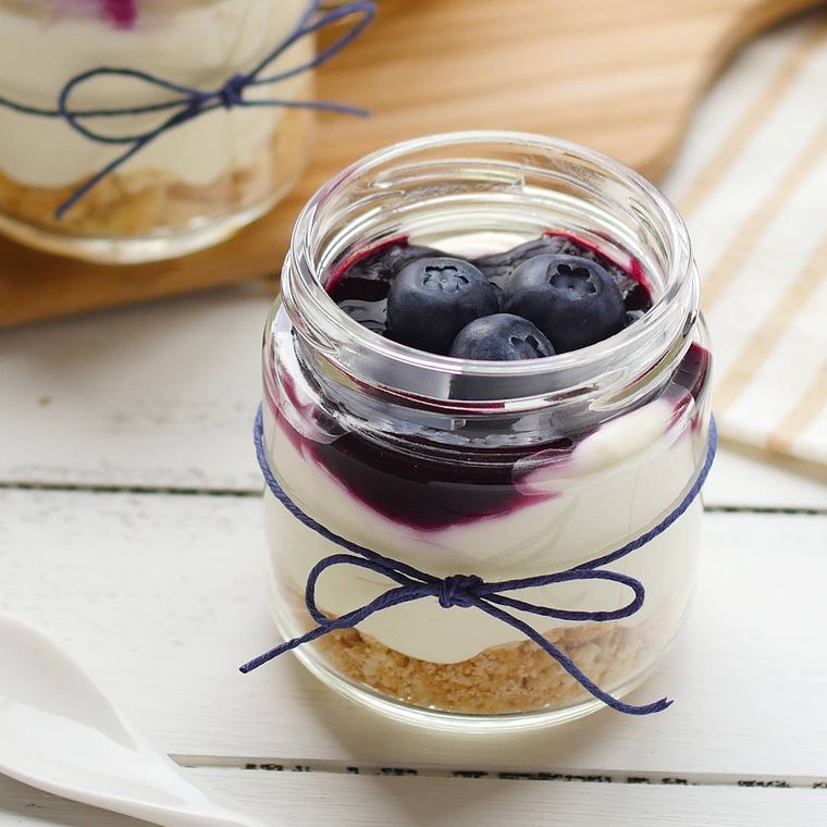 透明な瓶に入った、ブルーベリーソースがかけられているレアチーズケーキ