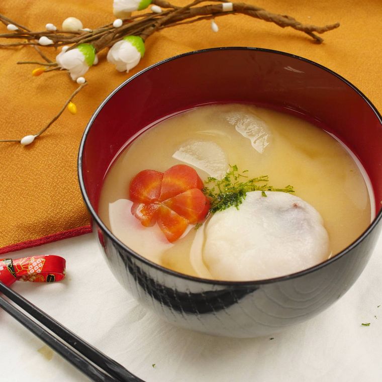 塗りのお椀に盛りつけられたあんこ餅とにんじん、大根の白みそ雑煮