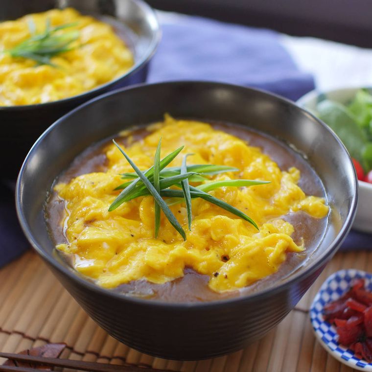 黒い丼鉢に盛りつけられたスクランブルエッグのカレーうどん
