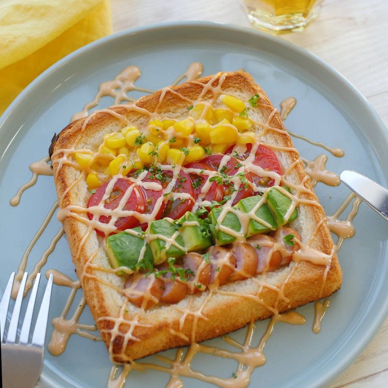 水色のお皿にのったコブサラダトーストに、フォークとナイフが添えられている様子