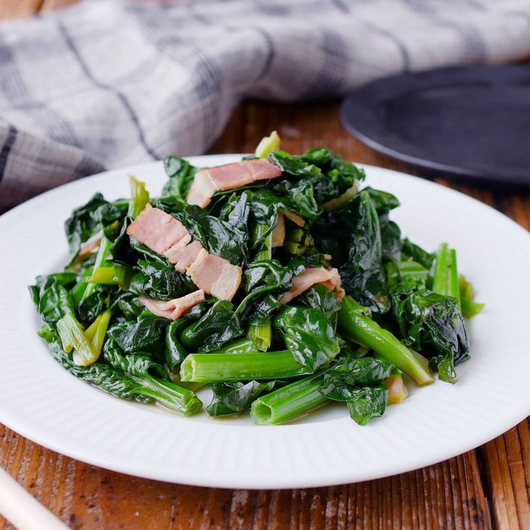 白い皿に盛り付けられているちぢみほうれん草のバターしょうゆ炒め