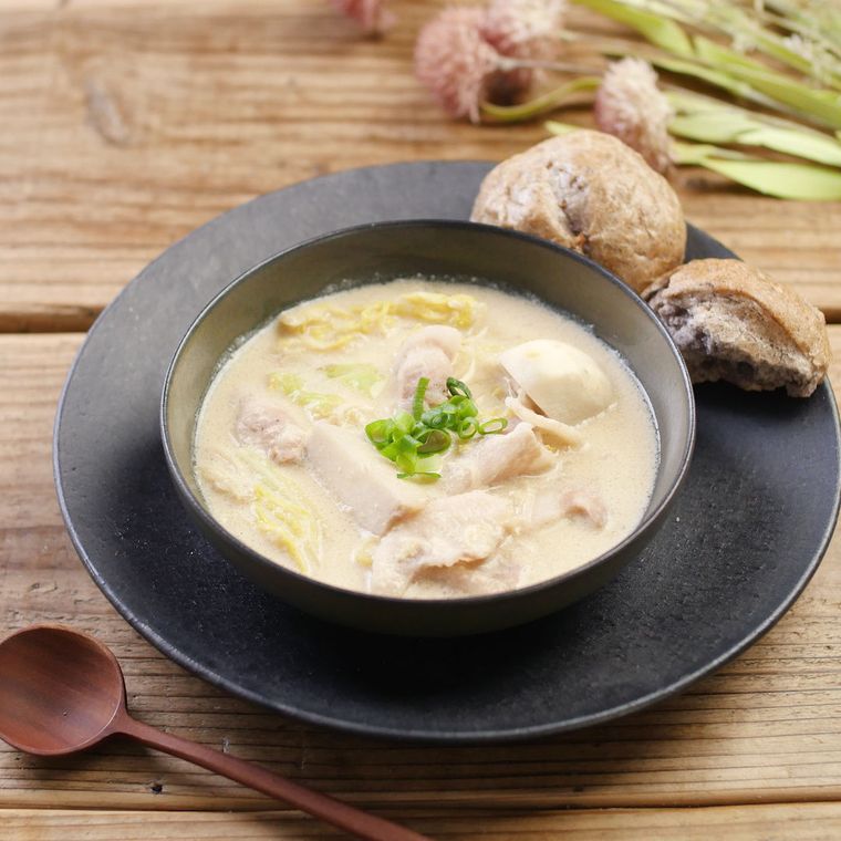 黒い皿に盛りつけられた豆乳キャベツスープとパン