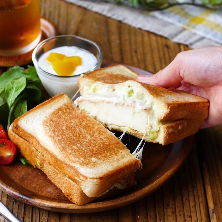 木製の皿に盛られた厚揚げホットサンドを手で持ちあげている様子