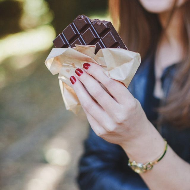 食べかけのチョコレートを持つ女性の写真