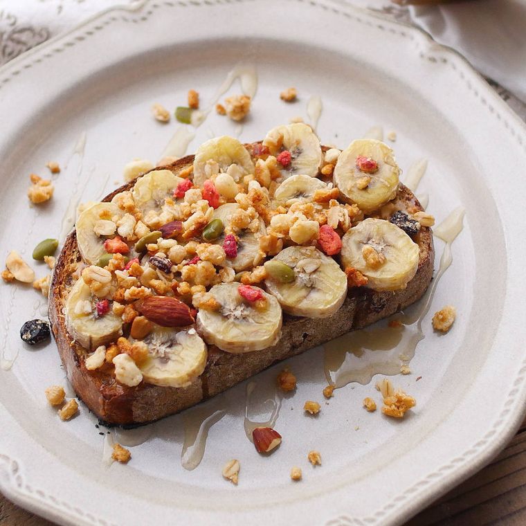 白い皿に盛り付けられたピーナッツバターバナナのグラノーラトースト