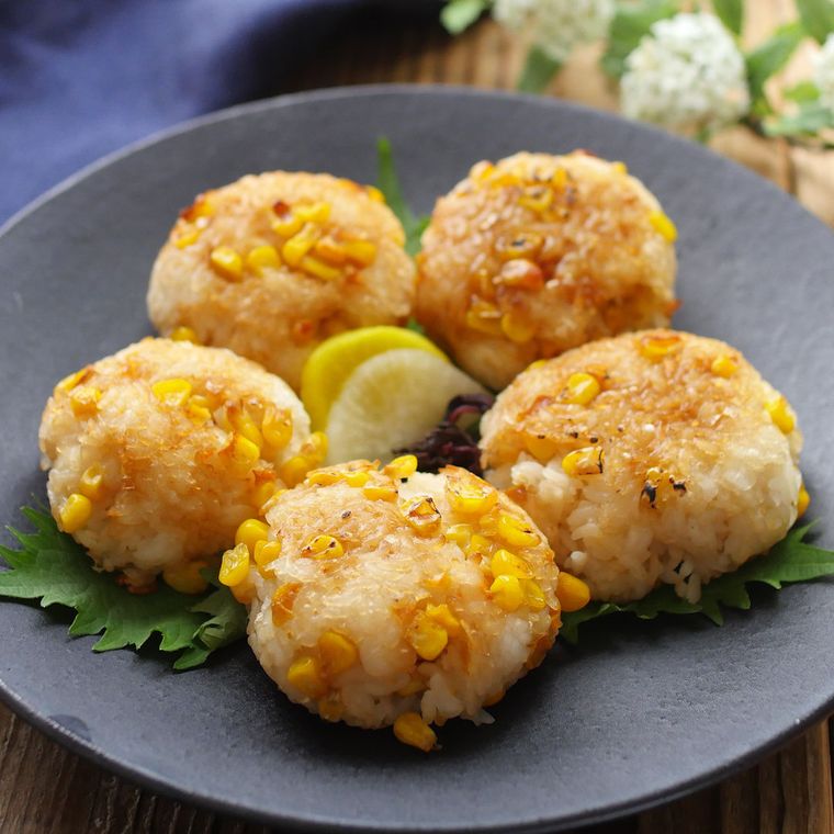 焼きもろこしおにぎりが丸いお皿の上に5個盛られていて、真ん中には漬物が置いてある