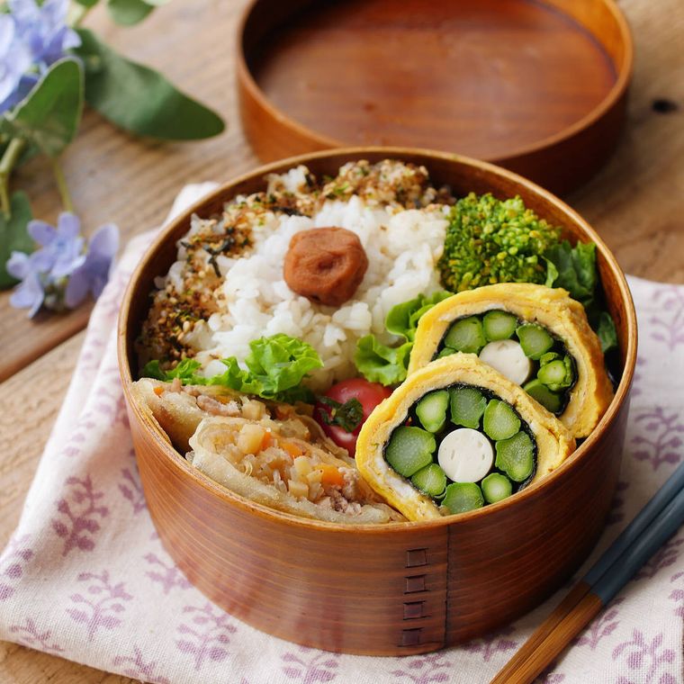弁当箱に詰めたアスパラガスのお花卵焼きやごはんなど